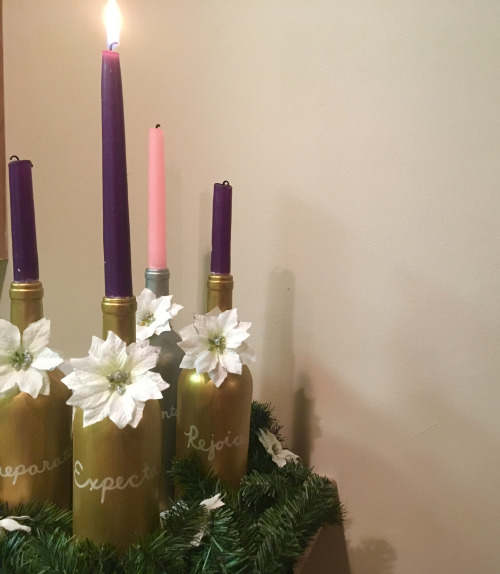 4 gold painted wine bottles and a silver one holding purple and pink candles